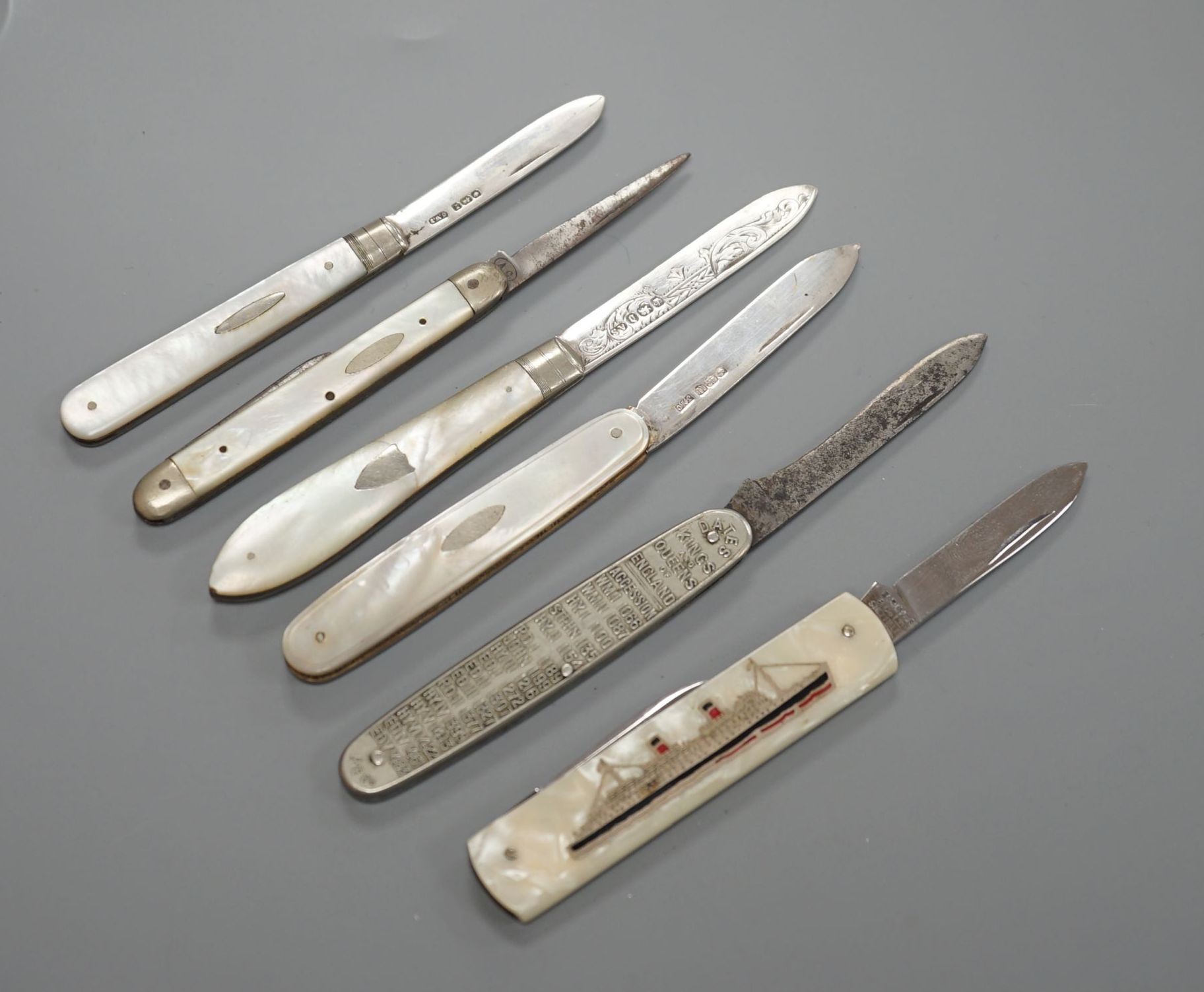 Three assorted mother of pearl mounted silver bladed fruit knives, one other penknife and two commemorative pocket knives.